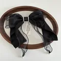 Detail of a large black satin bow hair clip with layered mesh and elegant pearl accents - Black