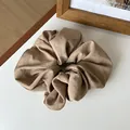 Detail of earthy brown matte fabric scrunchie with natural soft pleated texture - Light Coffee