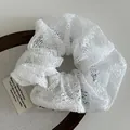 Eleganter Haargummi aus weißer Spitze mit Hohlstickerei auf einem Display-Tablett - Weiß