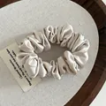 Detailed texture of champagne satin scrunchie fabric with elegant pleated folds - Beige