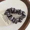 Close-up of a dark brown satin scrunchie displayed on a minimalist wooden tray - Dark Gray