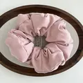 Close-up of pink puffy cotton scrunchie texture and soft pleats on rustic wooden tray - Pink