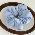 Close-up of a light blue cloud-style fabric scrunchie on a minimalist wooden tray - Blue
