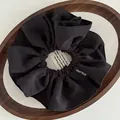 Detail of a large black fabric scrunchie with handmade tag in a wooden tray - Pleated Handmade Label Style / Black