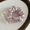Elegant dusty pink satin scrunchie with silky pleated texture on a wooden tray - Pink