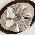 Minimalist beige oversized fabric scrunchie with handcrafted woven tag in a wooden tray - Pleated Handmade Label Style / Beige