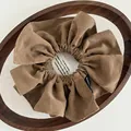 Brown suede scrunchie with visible stitching and woven label in a vintage wooden tray - Pleated Handmade Label Style / Brown