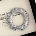 Detalle de coletero de satén plateado con textura plisada suave y brillo metálico elegante - Gris Plata