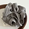 Detailed view of a dark grey ruffled fabric scrunchie on a wooden tray with soft lighting - Gray