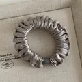 Elegante coletero de satén champán con un detalle de cuenta cilíndrica mate con estilo - Café Claro