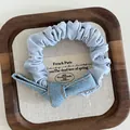 Light blue denim scrunchie with a knotted bow and contrasting yellow stitching detail - Denim Blue