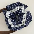 Detail eines dunkelblauen Polka-Dot-Haargummis mit feiner weißer Spitzenborte - Marineblau