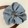 Light blue fabric scrunchie in a wooden tray with a minimalist textile background - Blue