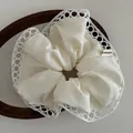 White handmade fabric hair scrunchie with hollow lace edges and artisanal woven label - Off-white