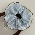 Close-up of blue plaid scrunchie with white ruffles and brown stitching detail - Plaid Style Blue White Check