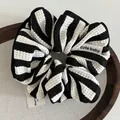 Chouchou rayé noir et blanc avec texture gaufrée et étiquette sur plateau en bois - Noir