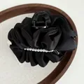 Elegant black satin pleated hair claw clip with white pearl accents on wooden tray - Black