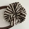Primer plano detallado del coletero de punto con rayas marrones y beige en bandeja de madera - Rayas marrones
