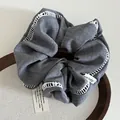 Detailed close-up of grey fabric hair scrunchie with white lace trim on wooden tray - Gray