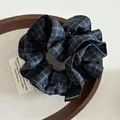 Dunkelblauer karierter Stoff-Scrunchie mit Handmade-Label auf Holztablett - Marineblau