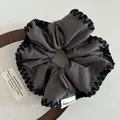 Detail of grey hair scrunchie with black hand-stitched edges and cute baby woven label - Gray