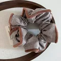 Gestreiftes Samt-Haargummi in Braun und Weiß mit Plüschrand auf einem Holztablett - Braun