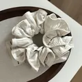 Eleganter cremefarbener Haargummi aus plissiertem Stoff mit gesteppter Textur - Cremeweiß