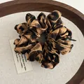 Detailed view of leopard print fabric scrunchie with handmade tag on a wooden tray - Brown Black Leopard (Style C)