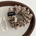 Detail of leopard print fabric scrunchie with a Hand Made label in a wooden tray - Khaki Leopard (Style B)