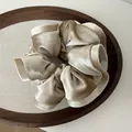 Glossy champagne gold velvet scrunchie with elegant pleated design on a wooden tray - Beige Apricot