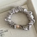 Detail view of satin hair scrunchie with crystal beads and metallic champagne sheen - Apricot