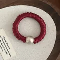 Close-up of pleated dark red satin scrunchie with a large champagne imitation pearl - Burgundy