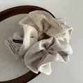 Detail van crème gebreide scrunchie met lovertjes en zwart Hand Made geweven label - Melk Abrikoos