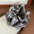 Macro di un grande elastico scrunchie a quadri blu e marroni con spessi bordi cuciti - Blu Caffè