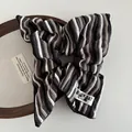 Détail d'un chouchou en tricot rayé avec étiquette sur un cercle à broder en bois - Gris Vintage