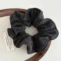 Detailed macro view of dark grey wool fabric texture on a soft oversized scrunchie hair tie - Black