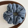 Close-up of soft navy and grey striped knit scrunchie on a wooden tray with linen lining - Blue