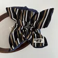 Détail d'un chouchou en tricot rayé avec étiquette tissée Black Cat sur plateau bois - Bleu Denim