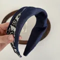 Detail eines blauen Denim-Haarreifens mit schwarz-weißem Stofffutter und Knotendesign - Navy Weiß