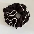 Detalle de coletero de lana marrón oscuro con bordes bordados blancos y pliegues decorativos - Marrón