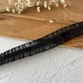 Close-up of black elastic pleated ruffle lace trim for DIY sewing and wedding dress detail - Black