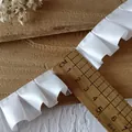 Macro view of 2.5cm wide white pleated satin ribbon for garment DIY and sewing projects - White