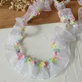 Detail von 2 cm gefalteter weißer Netzkante mit bunten floralen Quasten auf Holzhintergrund - Standardausführung / Weiß