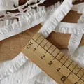 Dettaglio di nastro elastico pieghettato bianco da 1cm con finitura satinata e righello - Stile Stretto a Volant