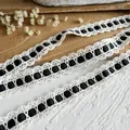 Dettaglio macro di pizzo bianco all'uncinetto con nastro di raso nero per cucito fai da te - Nero
