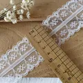 Detailed view of 5.5cm wide white floral lace trim on a rustic wooden background - Style One Wide Style