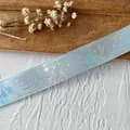 Dettaglio macro di nastro in mesh azzurro con farfalle e stampa olografica celeste - Azzurro Chiaro Con Finitura Argento Lucido Decorato Con Un Motivo A Farfalla. Lungo 9 Metri E Largo 25 Cm. (versione Migliorata)