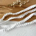 Λευκή τρέσα με πομ πομ για χειροτεχνίες και διακόσμηση ρούχων σε ξύλινο φόντο - Λευκό