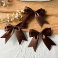 Drei dunkelbraune Satin-Haarschleifen mit eleganten Bändern auf rustikalem Holzgrund - Doppellagige Schleife / 5 Stück/Packung (Bandbreite 2,5 cm) / Dunkelkaffee