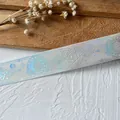 Close-up of holographic gradient ribbon with geometric star patterns for DIY crafts - Length 18m Width 2.5cm / White Base Silver Print